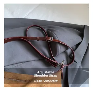 Detail showing adjustable burgundy leather shoulder strap with silver buckle on tote bag