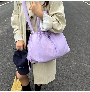 Close-up of light purple quilted puffer bag with drawstring details and wide strap