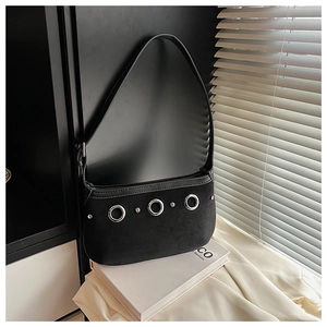 Detail view of black suede baguette bag with silver metal rings and punk rivet accents