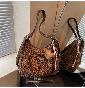 Detail of leopard print tote bag with brown leather straps and plush bear charm decoration