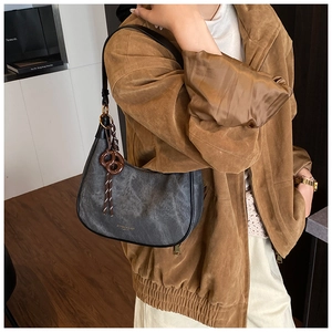 Close-up of gray vintage hobo bag with matte leather texture and brown woven charm detail