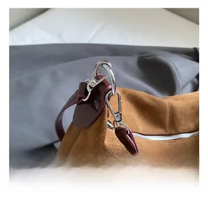 Detail of brown suede tote bag with silver metal spring hook and premium leather strap