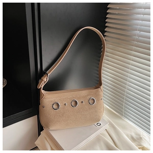 Detail of suede underarm bag with silver grommets and rivets against blinds shadow