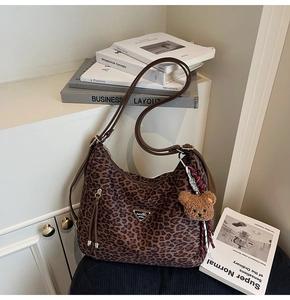 Close-up of leopard print tote bag with teddy bear charm and metal logo plaque