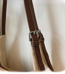 Detail of premium silver buckle and adjustable brown leather strap on canvas tote bag