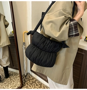 Detail of black pleated cloud shoulder bag showing ruched texture and knotted strap design