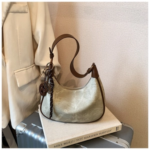 Detail of a vintage half-moon underarm bag with beige canvas and metal charm