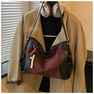 Detail of suede and leather tote with bead charm and polished metal logo branding