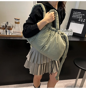 Detail of olive green quilted nylon tote bag featuring puffer texture and drawstring closure