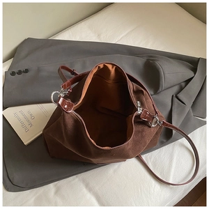 Detail of brown suede tote bag featuring bright orange lining and silver hardware zip
