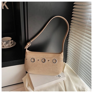 Detail shot of khaki suede shoulder bag featuring silver metal grommets and rivets