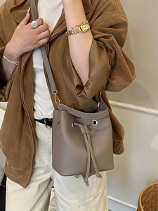 Minimalist leather bucket bag in taupe with drawstring and gold-tone hardware crossbody style