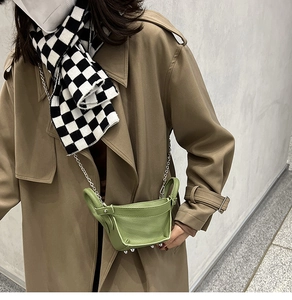 Detail of green lychee leather bucket bag with silver chain strap and metal rivet bottom