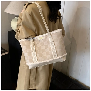 Close-up of beige jacquard tote bag with fleece trim and gold plate on shoulder