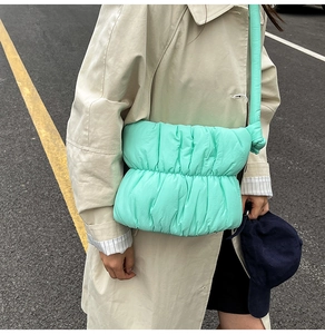 Detail of mint green quilted puffer cloud bag with wide shoulder strap and knot