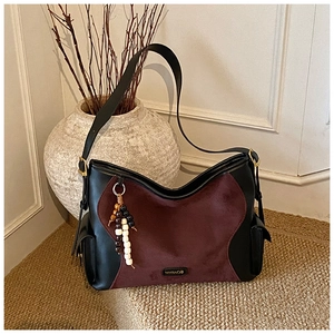 Detail of hobo bag featuring black leather, burgundy suede, and colorful beaded charm