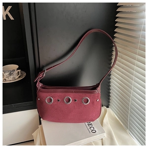 Detail of burgundy suede shoulder bag featuring three silver metal rings and chic rivets