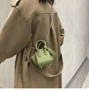 Detail of green litchi leather mini bucket bag with chain strap on trench coat