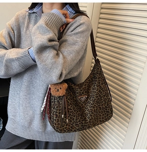 Close-up of leopard print hobo bag with leather strap and cute bear plush charm