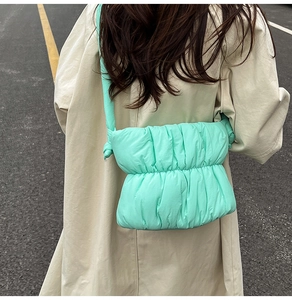 Mint green quilted puffer crossbody bag styled with a beige trench coat for a casual look
