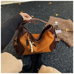 Close-up of a suede shoulder bag with retro color-block design and wooden bead charms