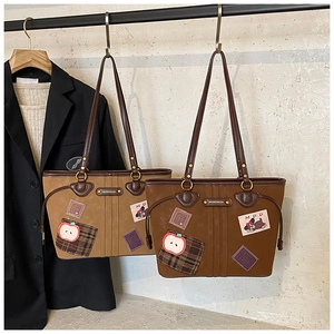 Détail de sacs fourre-tout marron vintage avec écussons brodés sur présentoir chic