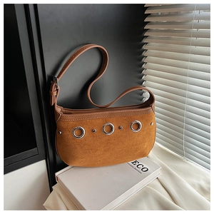 Detail of suede crossbody bag in ginger yellow with stylish silver metal eyelet accents