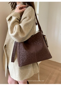 Detail of dark brown leopard print tote bag with vintage texture and gold zipper accent