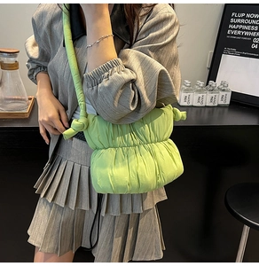 Detail of bright green quilted puffy crossbody bag with knot shoulder strap design