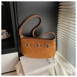 Macro shot of caramel suede shoulder bag with decorative metal eyelets and rivets