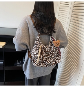 Detail of hobo bag with leopard print canvas texture and plush bear charm accessory