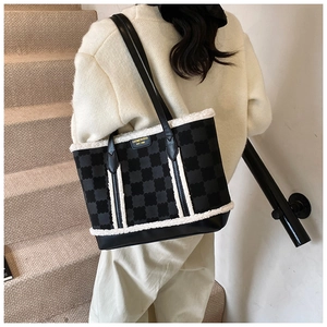 Detail of checkered tote bag featuring plush faux fur trim and gold-tone metal logo plaque
