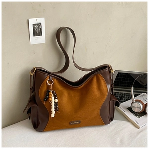Detail of hobo bag with suede patchwork, wooden bead charm and brown leather texture