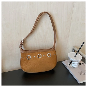 Detail shot of brown suede shoulder bag featuring decorative metal rings and rivets