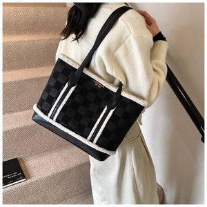 Detail of black tote bag featuring textured clover pattern and white faux fur trim
