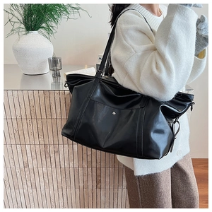 Détail du grand sac cabas en cuir ciré noir avec bouton pression et bandoulière réglable