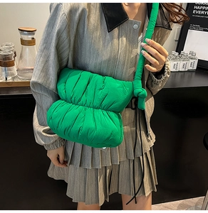 Detail shot of bright green quilted puffer bag with knotted strap and soft puffy texture