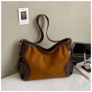 Detail of suede tote bag with metal logo, laptop and headphones in office setting