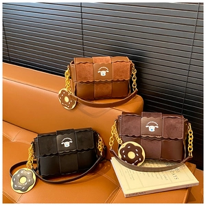 Detail of three retro leather crossbody bags with gold chain straps on a brown sofa