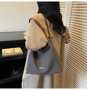 Detail of grey canvas tote bag featuring brown leather straps and branded woven label