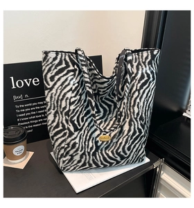 Dettaglio della borsa tote zebrata con una placca logo dorata sulla superficie tessile