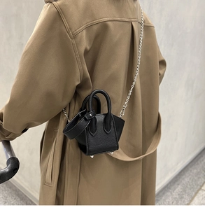 Detailed macro view of black pebble leather mini bucket bag with silver chain strap