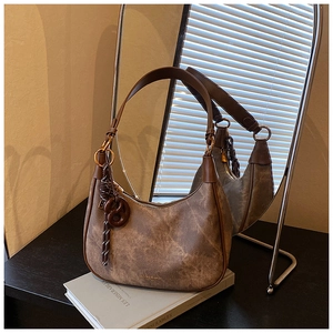Detail of vintage brown hobo bag on a book with soft natural lighting and leather texture
