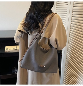Deep grey suede shoulder bag with brown strap shown from a side back view on a model