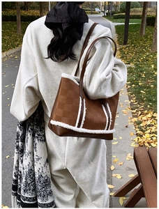 Close-up of brown tote bag with clover patterns and soft white shearling trim detail