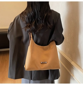 Rear view of model wearing a large ginger canvas tote bag over a black blazer