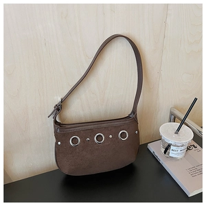 Detail of silver metal rings and rivets on brown suede shoulder bag with retro texture