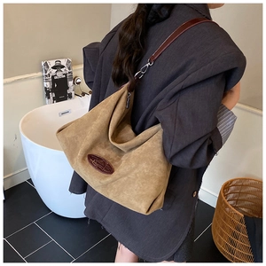 Detail view of a brown suede large tote bag with dark leather straps on a model