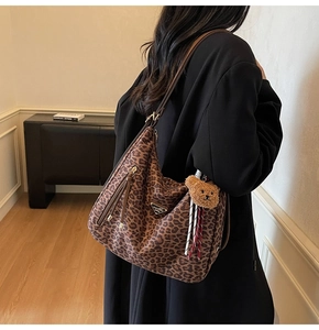 Detail view of leopard print shoulder bag with metal logo and plush bear pendant