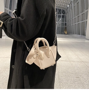 Close-up of beige litchi grain mini bucket bag with silver chain and metal studs